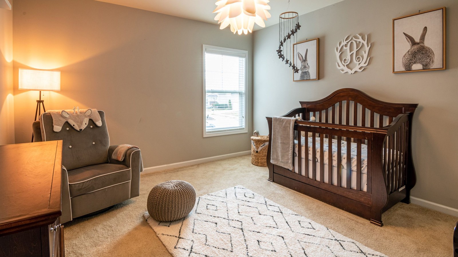 An empty wooden crib with a bare fitted sheet in a calm nursery, with no pillows, blankets, or toys inside it