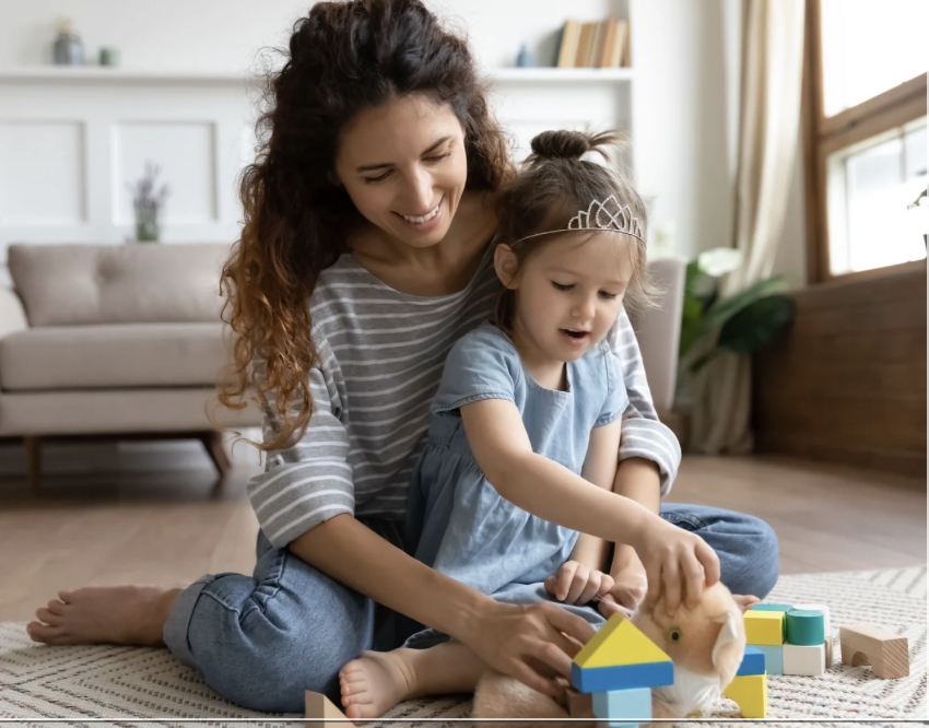 Mother and child playing with blocks together on floor