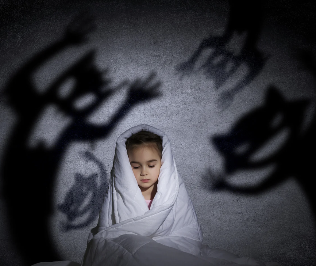 Child wrapped in white blanket with scary shadows on the wall