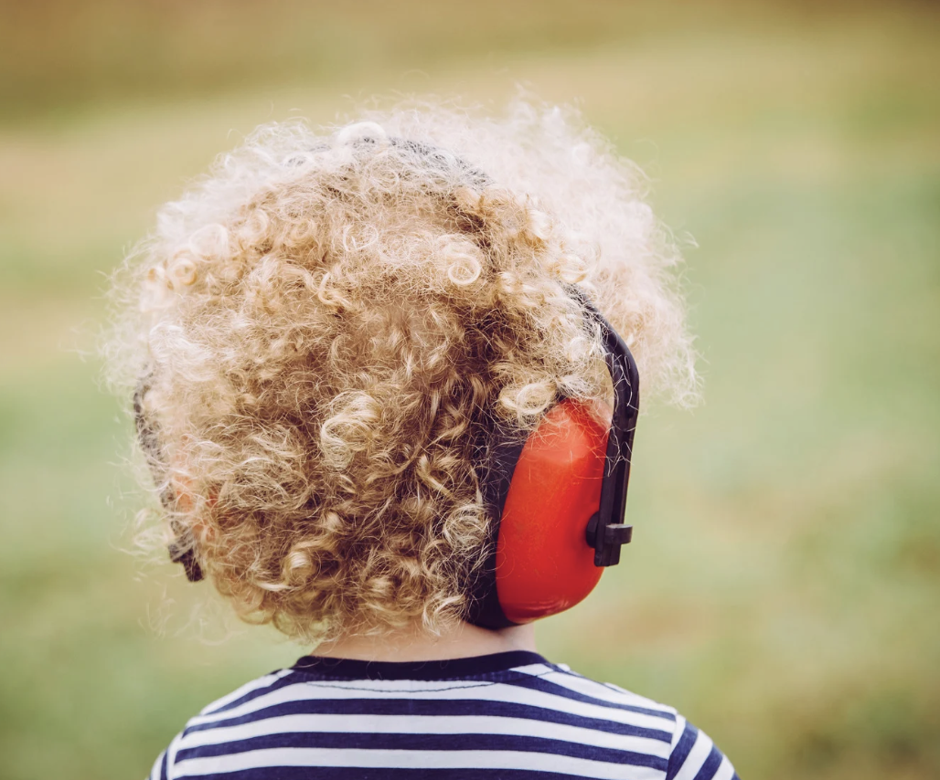 Child with curly hair wearing noise-cancelling headphones