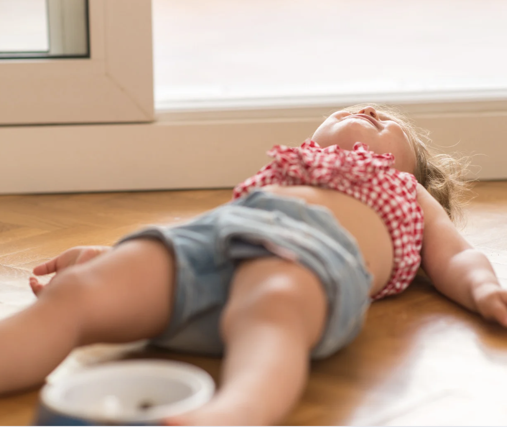 Toddler lying on wooden floor during a tantrum