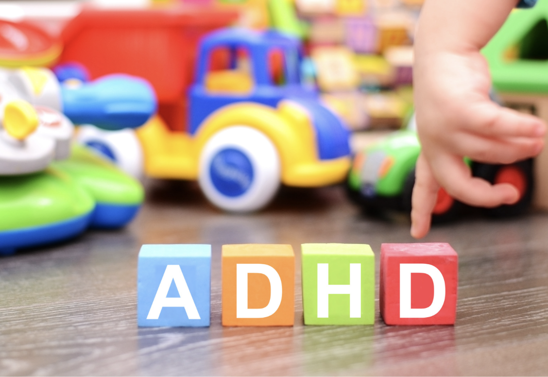 Colorful ADHD letter blocks on the floor with a child reaching toward toys