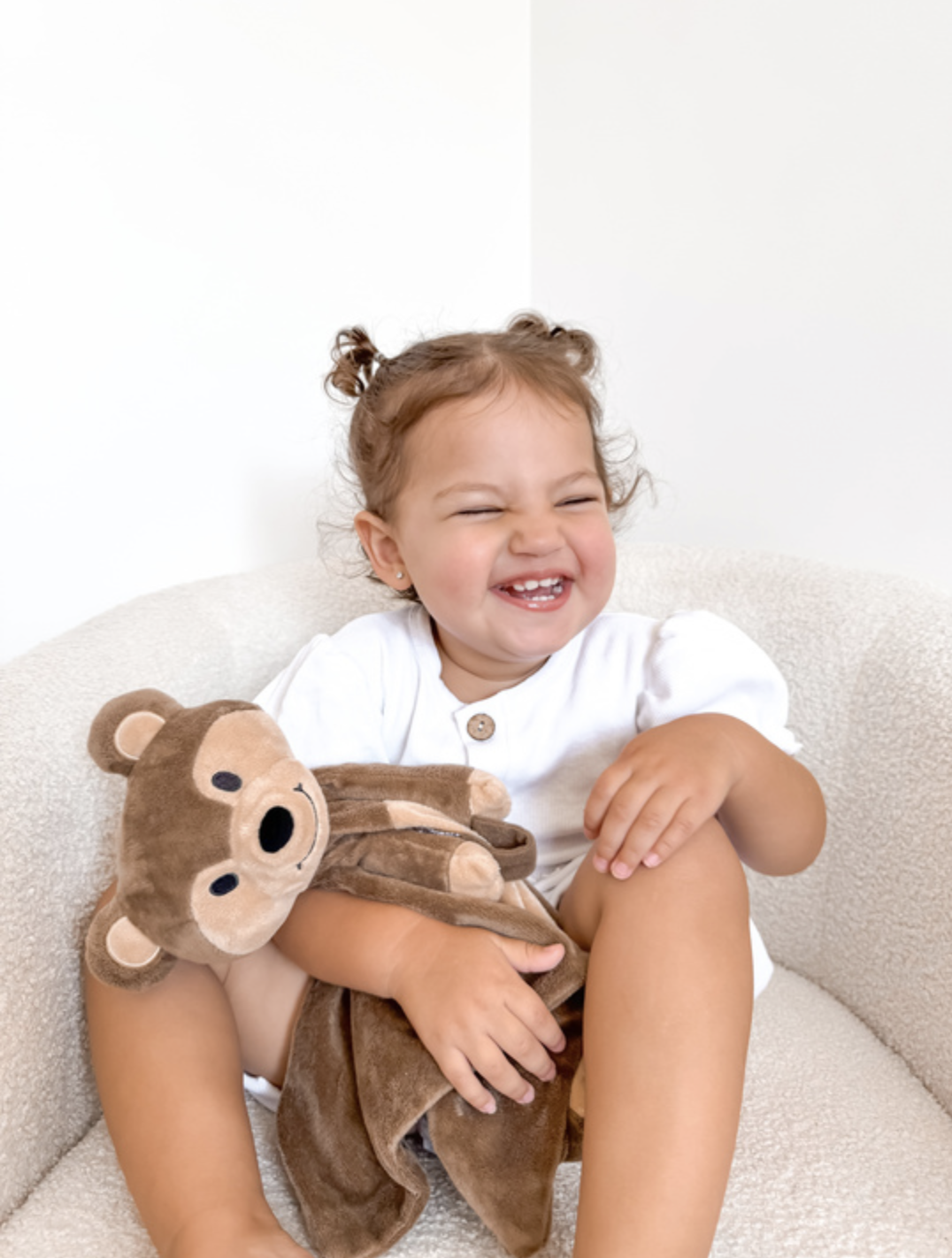 Happy toddler smiling and holding a teddy bear comforter - comfort tools and gentle sleep strategies collaboration